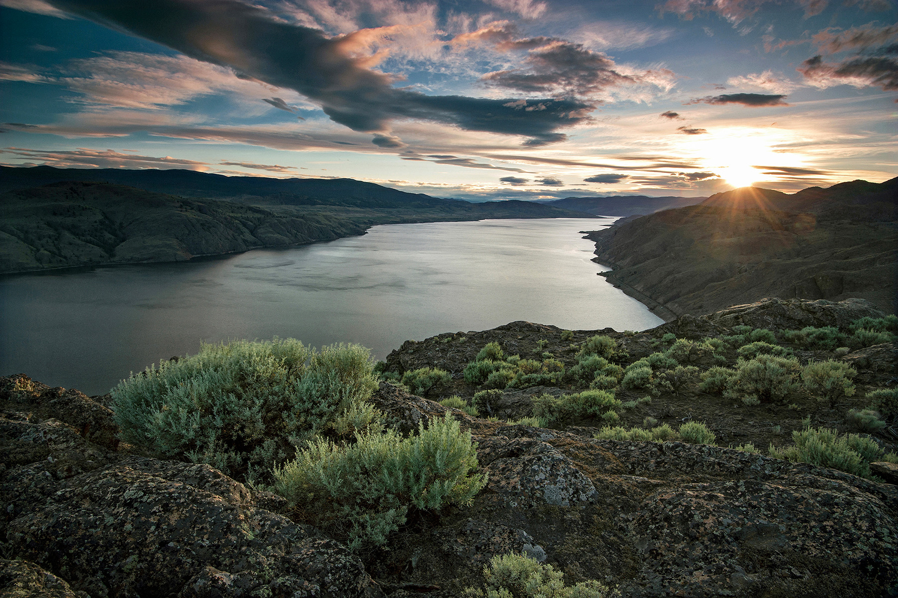 Kamloops Lake at sunset seen from the Battle Bluffs, with grassland hills and sagebrush in the foreground